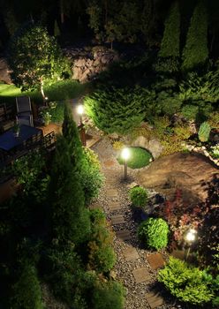 Beautiful patio illumination lights in lush garden evening top view