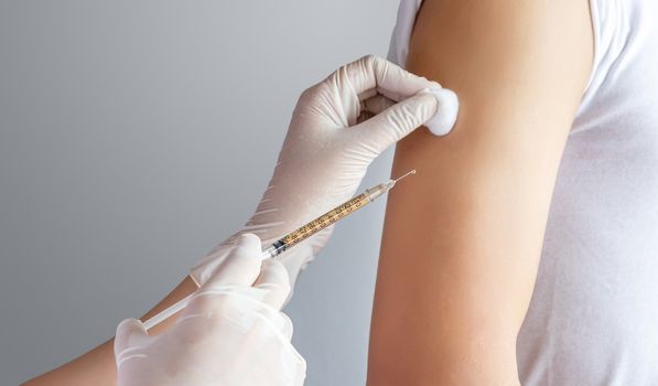 close-up of doctor, medical staff treating patient by injecting medicine in the upper arm at clinic or hospital. health care , treatment and vaccination concept