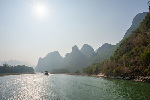 Boat on Li river cruise and karst formation mountain landscape in the fog between Guiling and Yangshuo, Guangxi province, China