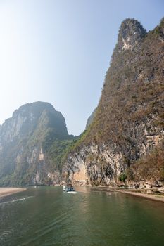 Boat on Li river cruise and karst formation mountain landscape in the fog between Guiling and Yangshuo, Guangxi province, China