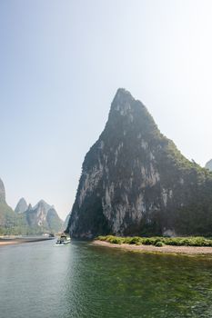 Boat on Li river cruise and karst formation mountain landscape in the fog between Guiling and Yangshuo, Guangxi province, China