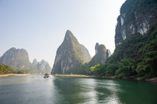 Boat on Li river cruise and karst formation mountain landscape in the fog between Guiling and Yangshuo, Guangxi province, China