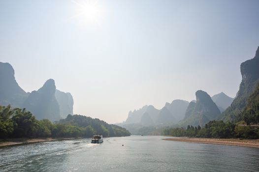Boat on Li river cruise and karst formation mountain landscape in the fog between Guiling and Yangshuo, Guangxi province, China