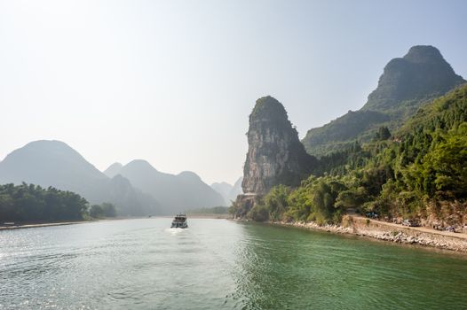 Boat on Li river cruise and karst formation mountain landscape in the fog between Guiling and Yangshuo, Guangxi province, China