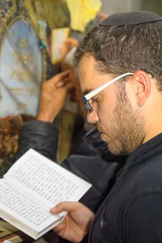 NETIVOT, ISRAEL - JAN 13, 2016: Jewish men pray at the Rabbi Israel Abuhaseira (Baba Sali) tomb, while reaching the mark with their hands, as part of the annual hillula of his memory. Netivot, Israel