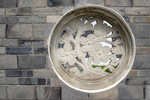 Traditional chinese stone fresco representing plants on a brick wall in HuanHuaXi public park, Chengdu, Sichuan province, China