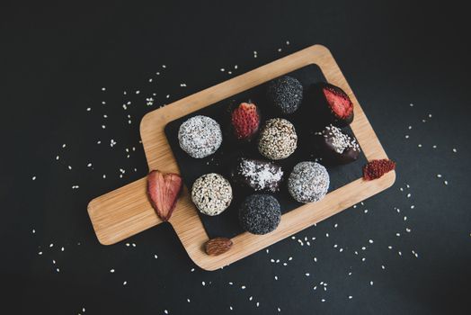 handmade sugar free and gluten free fruit and chocolate candies on a wooden board and black background