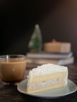 white chocolate cake with coconut cream filling served on white plate with a cup of coffee on the table. vertical image, cropped shot