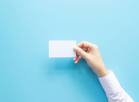 woman hand holding blank business name card paper isolated on blue background with copy space.