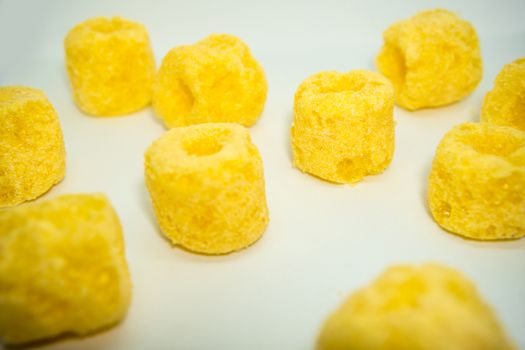 Baked corn snacks in tube shape on a white background