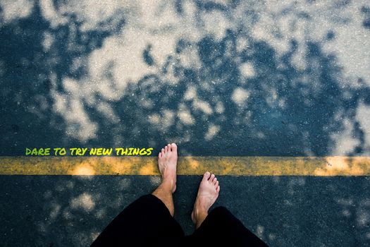 typography motivational messages and inspirational quotes. phrase DARE TO TRY NEW THING. Man's feet on the road with yellow line and shadow of trees background.