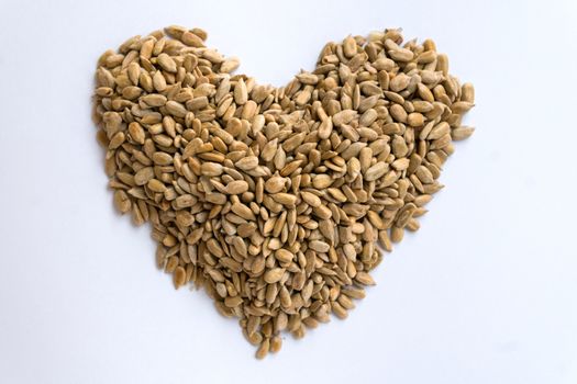 peeled sunflower seeds make a heart shape on white background