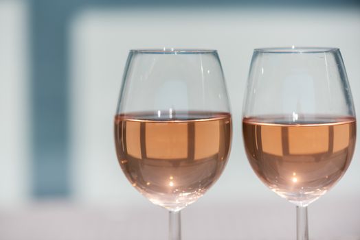 Two glasses of rose wine on a wooden table in sunlight