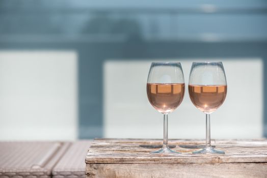 Two glasses of rose wine on a wooden table in sunlight