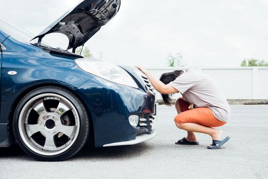 Asian woman 40s alone driver checking a car engine for fix and repair problem with unhappy and dismal between waiting a car mechanic from car engine problem at roadside