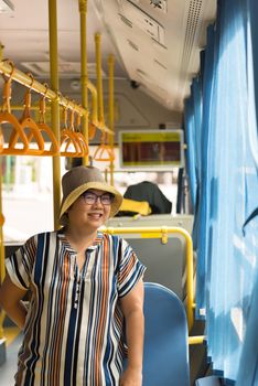 Asian woman 40s people travel by passenger bus in Bangkok city. Buses are one of the most important public mass transport system in Bangkok