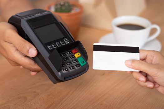 hand of customer using credit cart for payment at point of sale terminal in shop during shopping time, cashless technology and credit card payment concept