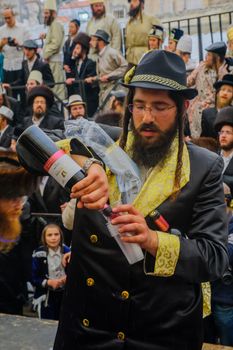 JERUSALEM, ISRAEL - MARCH 25, 2016: A man pour free wine to the crowd, as part of a celebration of the Jewish Holyday Purim, in the ultra-orthodox neighborhood Mea Shearim, Jerusalem, Israel