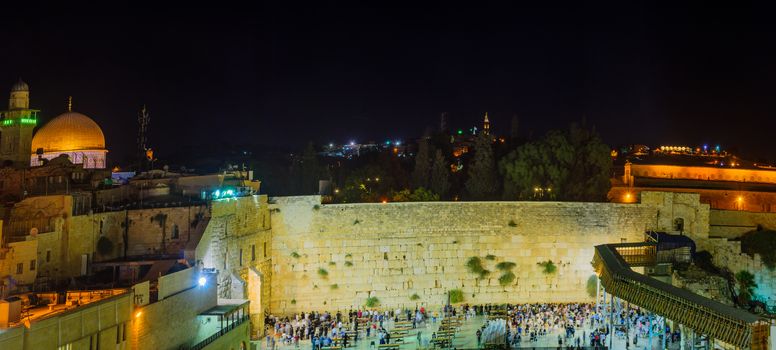 JERUSALEM, ISRAEL - SEPTEMBER 06, 2017:  Night scene of the Western Wall with Jewish prayers, and the Dome of the Rock in the background, in Jerusalem, Israel