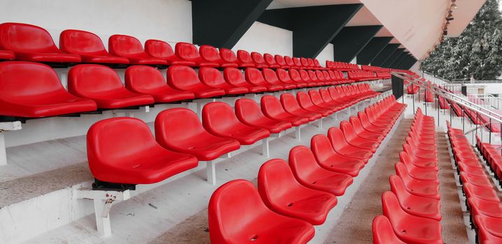 side view of empty red plastic seats row at football sport stadium. stadium seats background