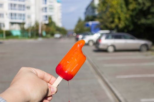 Ice cream melts in hands on the street against the background of machines