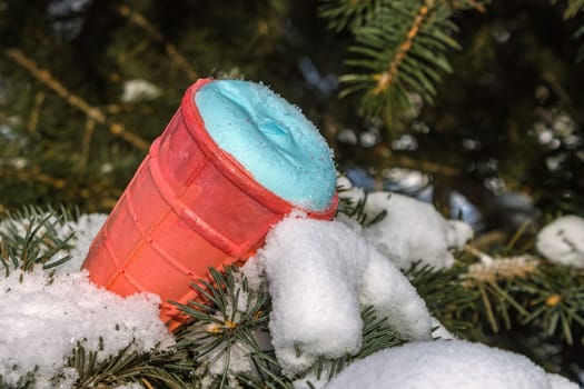 Sweet ice cream lies on the snowy branches of spruce in the park