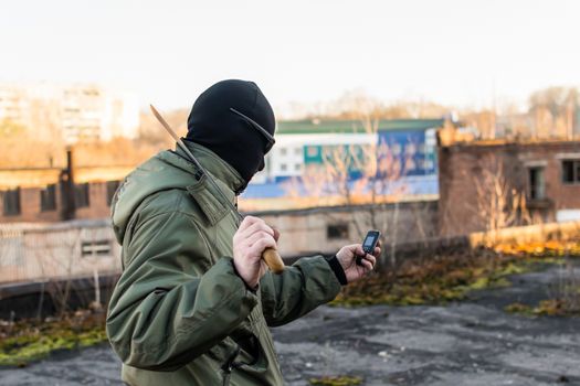 Criminal with a large knife looks into the phone