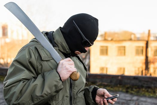 Criminal in a mask in a rage looks at the phone