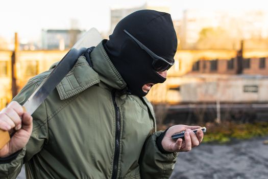 Criminal in a mask in a rage looks at the phone