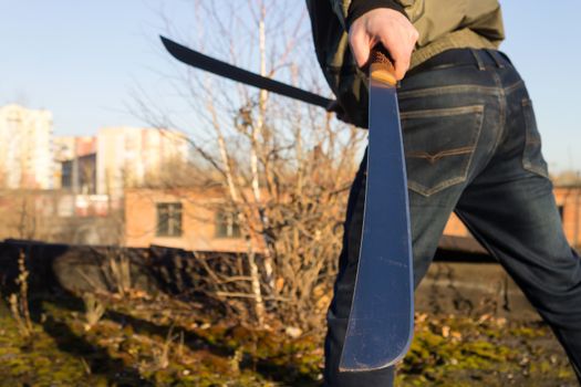 Machete close-up in the hands of a runaway criminal