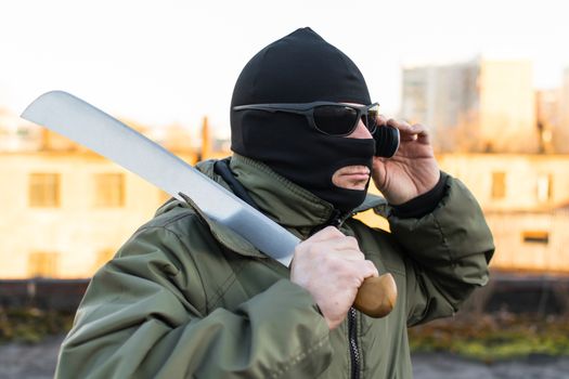 Bandit in a mask with a sword calls on the phone
