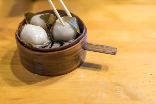 Glutinous rice dumplings wrapped in fresh leaves on a wooden table