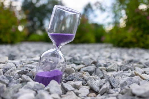 Hourglass close-up on the street in the park as a symbol of the passing time