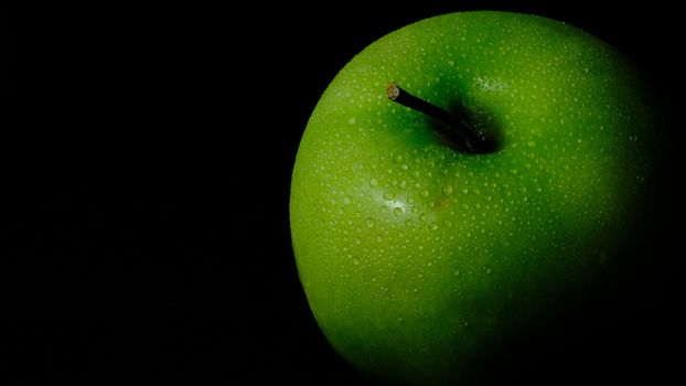 detail close up fresh green Apple with water droplet isolated on black background – low key macro shoot
