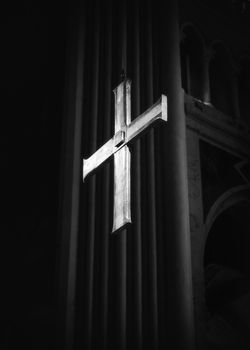 Shiny Christian cross in cathedral in black and white