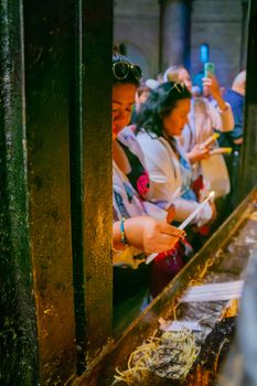 JERUSALEM, ISRAEL - APRIL 29, 2016: An Orthodox Good Friday scene in the church of the Holy Sepulcher, with women pilgrims lighting candles. The old city of Jerusalem, Israel