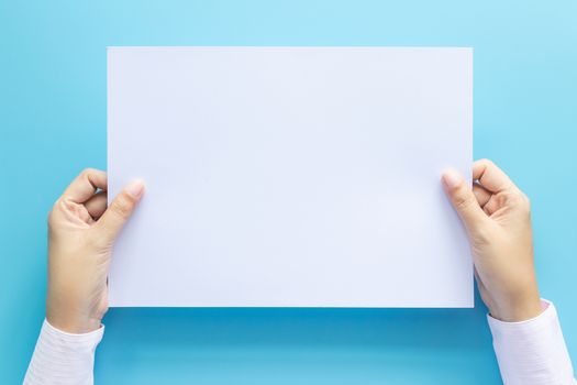 close up hands holding  empty white blank letter paper size A4 for flyer or invitation mock up isolated on a blue background.