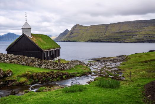 Small black wooden church in the village of Funningur situated on the sea shore. Funningur is located on the island of Eysturoy, Faroe Islands, Denmark