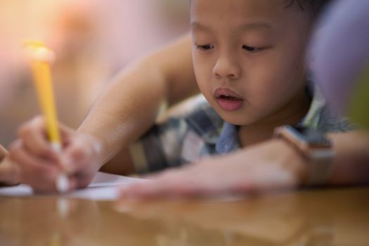 Boy is teached by hold hand writing by mom