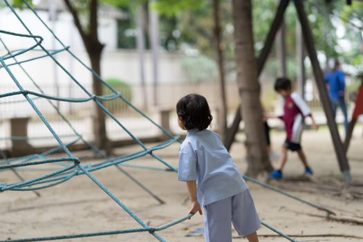 bioy kid in uniform play ropr climb in playground