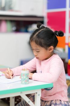 cute asian thai girl child kid sit and draw coloring homework on table happy cheerful