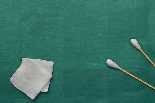 Gauze and swab cotton bus sticks on green medical surgical dress with copy space
