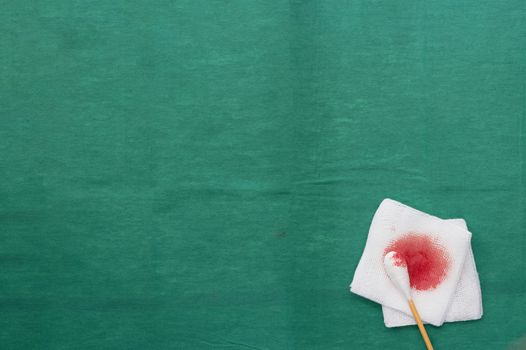 Gauze,blood and swab cotton bus sticks on green medical surgical dress with copy space
