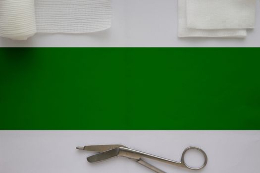 Gauzes, scissors and roll gauze on white background with green strip copy space