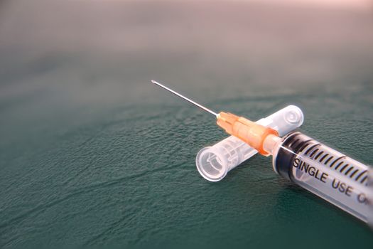 Medical care in syringe on cap and drug ampule broken in treatment hospital concept on green floor