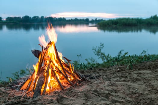 Beautiful bonfire by the river. Evening landscape