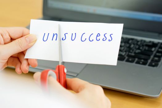 holds card with text unsccess on computer