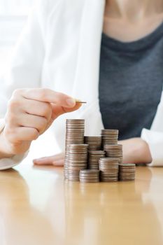 Businesswoman put coins to stack of coins