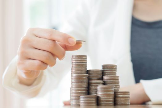 Close-up Of Businesswoman Putting Coin To Rising Stack Of Coins