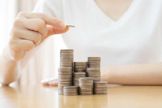Hand put coins to stack of coins on white background